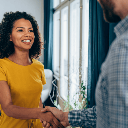 Two professionals shaking hands in an office setting with expressions of trust and confidence, representing Optimum Transitions' partnership-focused advisory approach